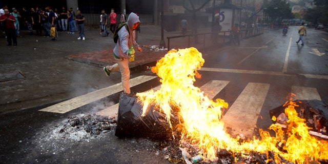 An opposition demonstrator sets a road block on fire in Caracas, Venezuela, Thursday, Feb. 12, 2015. Venezuelans staged dueling marches to mark the anniversary of last year's bloody protest movement that resulted in more than 40 people being killed, including both government supporters and opponents. Dozens of protesters remain jailed, while the social issues they railed against last year- a faltering economy, widespread shortages and pervasive violent crime - have only gotten worse. (AP Photo/Fernando Llano)