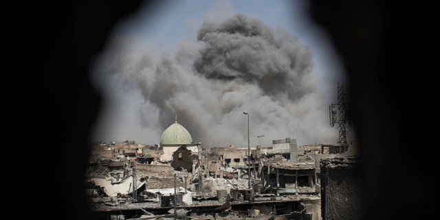 A bomb explodes behind the al-Nuri mosque complex, as seen through a hole in the wall of a house, as Iraqi Special Forces move toward Islamic State militant positions in the Old City of Mosul, Iraq, Thursday, June 29, 2017. (AP Photo/Felipe Dana)