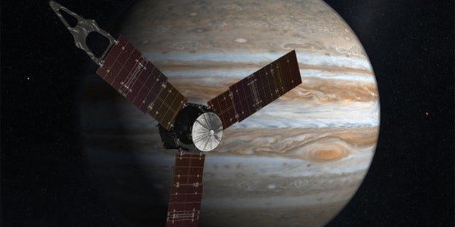 The Juno spacecraft passes in front of Jupiter in this artist's depiction.