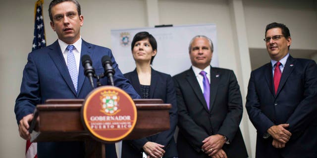 SAN JUAN, PUERTO RICO - NOVEMBER 14: Governor Alejandro Garcâa Padilla announces a 200 million dollar expansion of pharmaceutical operations of Eli Lilly in Puerto Rico at the Governor's Mansionon November 14, 2013 in San Juan, Puerto Rico, he was joined by (L-R) Chief of Staff Ingrid Vila, Secretary of Economic Development Alberto Baco, and Executive Director of the Puerto Rican Development Bank Antonio Medina Comas.The island-territory of the United States is on the brink of a debt crisis as lending has skyrocketed in the last decade with the government issuing municipal bonds. Since the tax exemption for american manufacturing companies expired in 2006 Mr. Garcâa Padilla said jobs in that sector have dropped from around 170,000 to about 80,000. (Photo by Christopher Gregory/Getty Images)