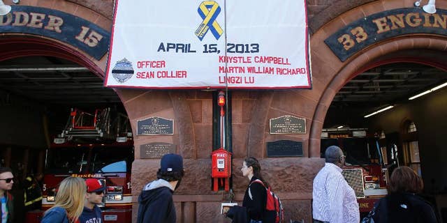 A banner honoring those killed at the 2013 Boston Marathon, and in the immediate aftermath, is draped on the front of Boston Fire Department's Engine 33 and Ladder 15, in Boston, Wednesday, April 15, 2015. Boston marked the second anniversary of the 2013 marathon bombings with a subdued remembrance that included a moment of silence, the pealing of church bells and a call for kindness. (AP Photo/Steven Senne)