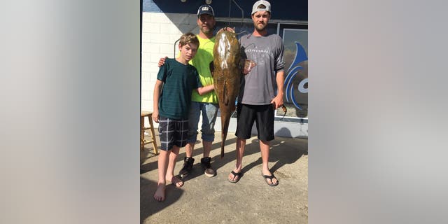 Virginia resident Jeffrey Dill and his family pose with the 68-pound flathead catfish he caught in Lake Smith.