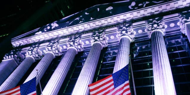 In this Wednesday, Oct. 8, 2014 photo, American flags fly in front of the New York Stock Exchange. U.S. stocks were barely higher in early trading Monday, Dec. 29, 2014, as Wall Street winds down the year in this holiday-shortened week. (AP Photo/Mark Lennihan)