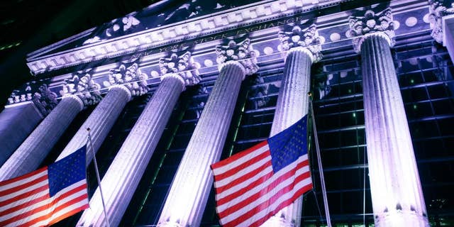 In this Wednesday, Oct. 8, 2014 photo, American flags fly in front of the New York Stock Exchange. U.S. stocks were barely higher in early trading Monday, Dec. 29, 2014, as Wall Street winds down the year in this holiday-shortened week. (AP Photo/Mark Lennihan)