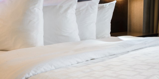 Neatly made hotel bed with 4 pillows.
