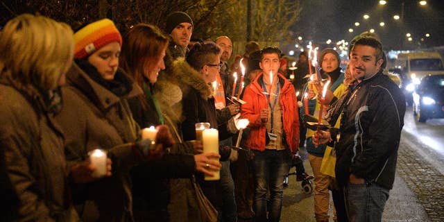 Participants with candles and torches stand on a bridge at the border between Austria and Germany during a demonstration for "Human refugee policy in a Europe without borders" in support of migrants, in Salzburg, Austria, Monday, Dec. 14, 2015. (AP Photo/Kerstin Joensson)