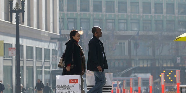 FILE - In this Tuesday, Dec. 24, 2013, file photo, a man and woman carry shopping bags as they cross the street in San Francisco. The Commerce Department reports how much consumers spent and earned in December. on Friday, Jan. 31, 2014. (AP Photo/Jeff Chiu)