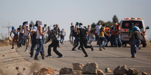 Palestinians run for cover from tear gas fired by Israeli security forces during clashes that occurred after the funeral of Palestinian Saed Dawabsheh, 32, in the West Bank village of Duma near Nablus on Saturday, Aug. 8, 2015. The father of a Palestinian toddler killed in a July 31 firebomb attack blamed on Jewish extremists has died of wounds sustained in the same incident, his family said Saturday. His 18-month-old toddler perished in the flames, while his 4-year-old brother and parents were seriously hurt. (AP Photo/Majdi Mohammed)