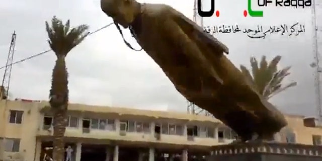In this Monday, March 4, 2013 image taken from video obtained from Ugarit News, which has been authenticated based on its contents and other AP reporting, a statue of former Syrian President Hafez Assad is pulled down in a central square in Raqqa, Syria.