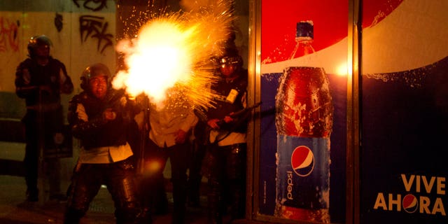 Un policía nacional bolivariano dispara gases lacrimógenos contra manifestantes antigubernamentales en Caracas, Venezuela, el sábado 22 de marzo de 2014. (Foto AP/Esteban Félix)