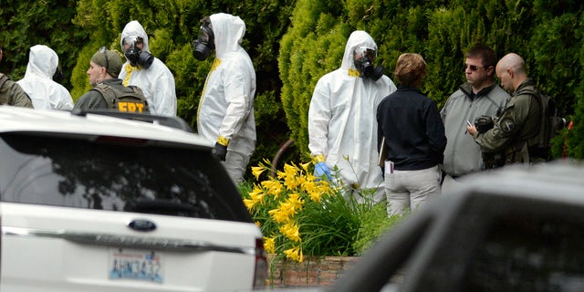 During the execution of a search warrant, members of the Joint Federal Haz-Mat Team, FBI, and local law enforcement gather in front of the Osmun Apartments near the intersection of First Avenue and Oak Street in Browne's Addition on Saturday, May 18, 2013 in Spokane, Wash. The search warrant is in connection with ricin-laced letters intercepted at a Post Office facility in Spokane earlier in the week. (AP Photo/TheSpokesman-Review, Colin Mulvany) COEUR D'ALENE PRESS OUT