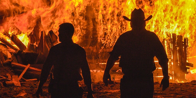 Investigators Kris Coughlin and Randy Patrick walk away from a burning house.