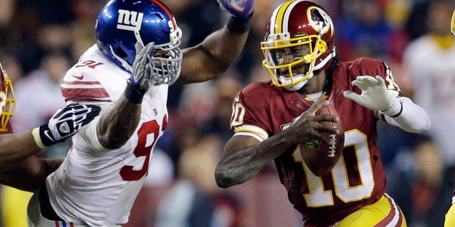 New York Giants defensive end Justin Tuck, left, tackles Washington Redskins quarterback Robert Griffin III (10) during the second half of an NFL football game Sunday, Dec. 1, 2013, in Landover, Md. (AP Photo/Patrick Semansky)