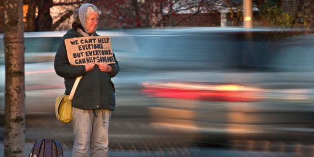 FILE - Nov. 14, 2013: Susan St. Amour, 54, a homeless woman, panhandles during the evening commute in Portland, Maine.