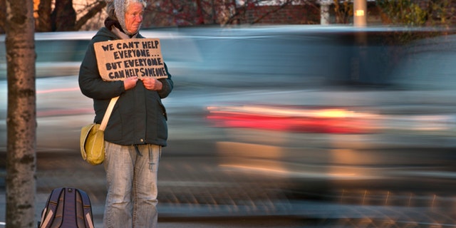 FILE - Nov. 14, 2013: Susan St. Amour, 54, a homeless woman, panhandles during the evening commute in Portland, Maine.