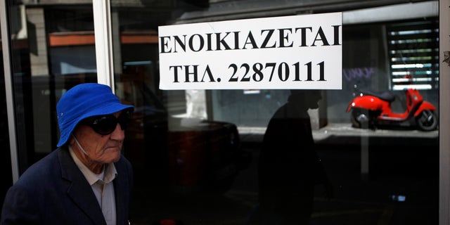 An elderly man passes an empty closed shop with a sign reading in Greek " To rent" in central Nicosia, Cyprus, Tuesday, April 9, 2013. Last month, Cyprus agreed that bondholders, investors and savers with more than 100,000 euros in the country's two largest — and most troubled — banks will take significant losses in exchange for a 10 billion euro ($13 billion) rescue package. (AP Photo/Petros Karadjias)