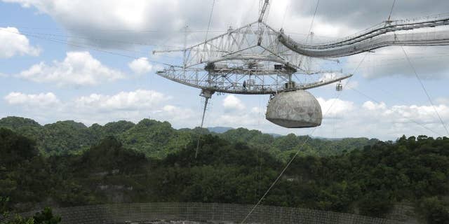 This July 13, 2016 photo shows the world's largest single-dish radio telescope at the Arecibo Observatory in Arecibo, Puerto Rico. Dwindling funds from the U.S. government and construction of bigger, more powerful telescopes in places like China and Chile are threatening this telescope's existence. It performs tasks like searching for gravitational waves, listening for extraterrestrial signals and tracking asteroids that might be on a collision course with Earth.  (AP Photo/Danica Coto)