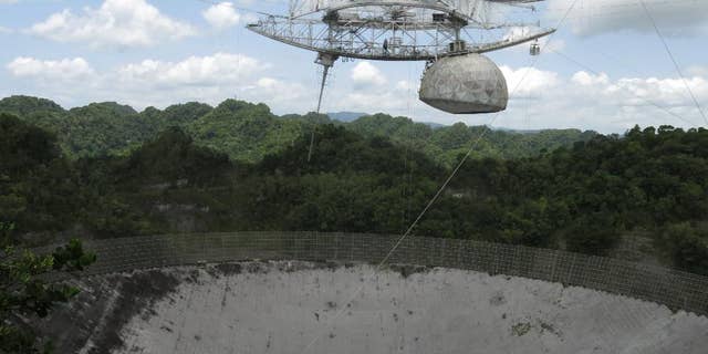 This July 13, 2016 photo shows the world's largest single-dish radio telescope at the Arecibo Observatory in Arecibo, Puerto Rico. Dwindling funds from the U.S. government and construction of bigger, more powerful telescopes in places like China and Chile are threatening this telescope's existence. It performs tasks like searching for gravitational waves, listening for extraterrestrial signals and tracking asteroids that might be on a collision course with Earth. (AP Photo/Danica Coto)