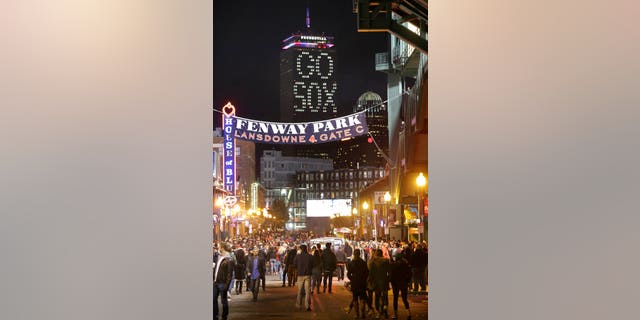 The words "Go Sox" are illuminated on a side of the Prudential Tower, top, as people walk along a street outside Fenway Park during Game 6 of baseball's World Series between the Boston Red Sox and St. Louis Cardinals, Wednesday, Oct. 30, 2013, in Boston. (AP Photo/Steven Senne)