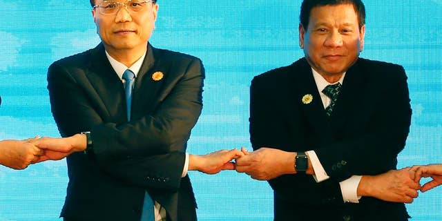 FILE - In this Sept. 7, 2016 file photo, Chinese Prime Minister Li Keqiang, left, and Philippine President Rodrigo Duterte link arms during the ASEAN Plus Three summit in the ongoing 28th and 29th ASEAN Summits and other related summits at the National Convention Center in Vientiane, Laos. After lashing out at longtime ally America, the new Philippine president is making a state visit to China in a charm offensive that will help define how far he wants to shift allegiance from treaty ally the U.S. to an Asian superpower locked in a territorial standoff with his small, impoverished country. (AP Photo/Bullit Marquez, File)