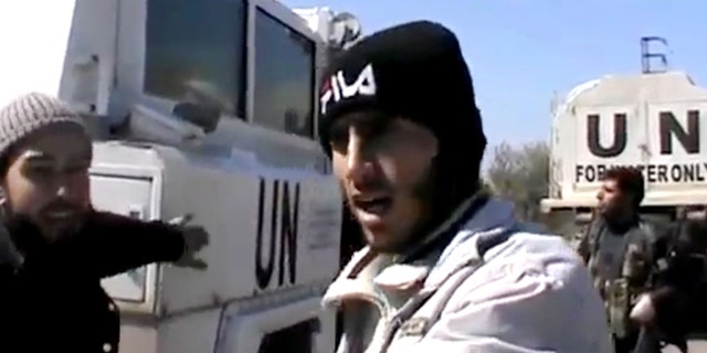 In this Wednesday, March 6, 2013 image taken from video obtained from the Ugarit News, which has been authenticated based on its contents and other AP reporting, Free Syrian Army fighters stand next to United Nations Disengagement Observer vehicles near Golan Heights in the southern province of Daraa, Syria.