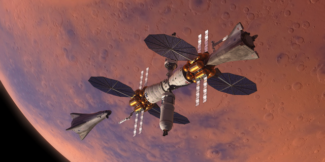 The surface landing vehicle for Lockheed Martin's Mars Base Camp is shown to the left of the space station in this artist's illustration.