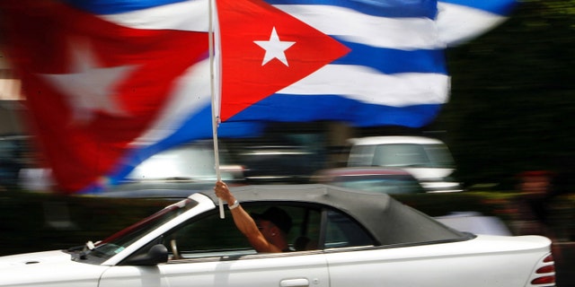 MIAMI - AUGUST 1: A motorist waves a Cuban flag while cruising down the famous Calle Ocho in the Little Havana neighborhood August 1, 2006 in Miami, Florida. Cuban Americans were celebrating the news that Fidel Castro had turned over power to his younger brother, Raul Castro, while he undergoes medical treatment for intestinal bleeding. (Photo by Chip Somodevilla/Getty Images)