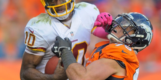 Washington Redskins quarterback Robert Griffin III (10) stiff arms Denver Broncos defensive end Derek Wolfe (95) in the fourth quarter of an NFL football game, Sunday, Oct. 27, 2013, in Denver. (AP Photo/Jack Dempsey)