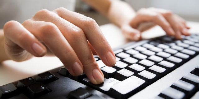 Close-up of female hands touching black computer keyboard buttons
