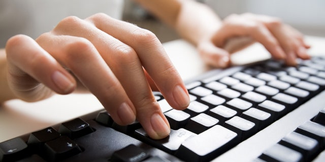 Close-up of female hands touching buttons of black computer keyboard