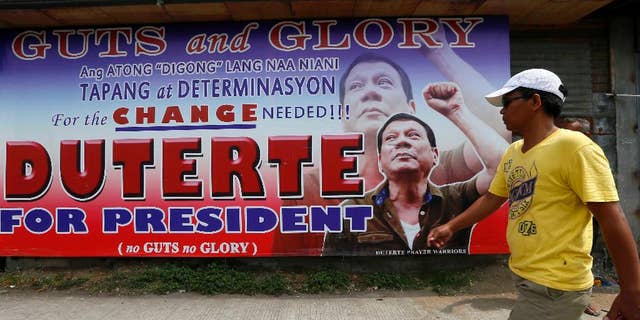 A resident walks past a campaign billboard of leading presidential candidate Mayor Rodrigo Duterte along a boulevard at his hometown in Davao city in southern Philippines Wednesday, May 11, 2016. Duterte has widened his lead in unofficial tally but still refuses to claim victory.(AP Photo/Bullit Marquez)