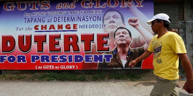 A resident walks past a campaign billboard of leading presidential candidate Mayor Rodrigo Duterte along a boulevard at his hometown in Davao city in southern Philippines Wednesday, May 11, 2016. Duterte has widened his lead in unofficial tally but still refuses to claim victory.(AP Photo/Bullit Marquez)