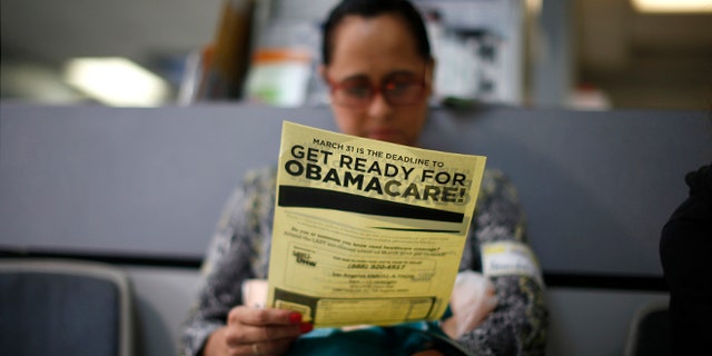 FILE: March 27, 2014: A woman reads a leaflet at a ObamaCare enrollment event in Cudahy, California