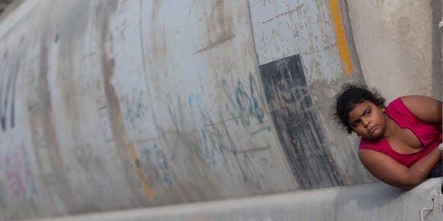 FILE - In this July 12, 2014, file photo, a young migrant girl waits for a freight train to depart on her way to the U.S. border, in Ixtepec, Mexico. According to a report by Human Rights Watch released Thursday, March 31, 2016, Mexico does not comply with its own laws on handling unaccompanied child migrants who arrive in the country fleeing violence in Central America. (AP Photo/Eduardo Verdugo, File)
