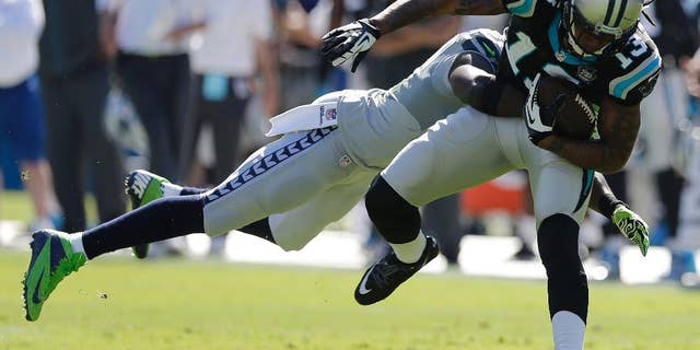 Carolina Panthers wide receiver Kelvin Benjamin (13) moves as Seattle Seahawks strong safety Kam Chancellor (31) tackles during the first half of an NFL football game, Sunday, Oct. 26, 2014, in Charlotte. (AP Photo/Chuck Burton)