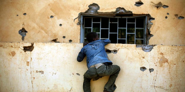 A Malian boy climbs the wall of the police station in Gao, northern Mali, Monday, Feb. 11, 2013, one day after Mujao fighters engaged in a firefight with Malian forces. French and Malian government forces have regained control of this northern city, after Islamic fighters fought a prolonged battle. Hospital officials and witnesses say three civilians died in the fighting Sunday. It is not known how many extremists and Malian troops died in the more than five hours of combat. (AP Photo/Jerome Delay)