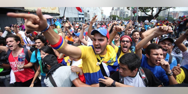 Opposition students shouts slogans against supporters of Venezuela's late President Hugo Chavez during a protest a few blocks from the electoral commission in Caracas, Venezuela, Thursday, March 21, 2013. The students were asking that the commission eliminate requirements that voters have their fingerprints recorded before voting. They were also demanding the government not interfere in politics ahead of an April 14 vote to replace Chavez. (AP Photo/Fernando Llano)