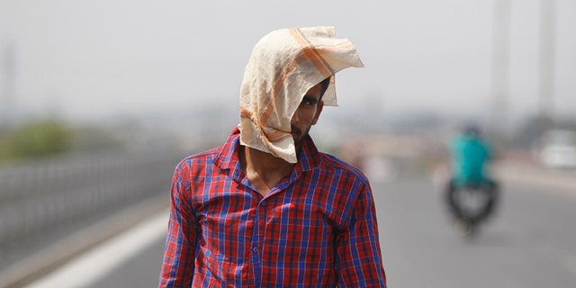 A man uses a cloth to protect himself from the sun during a hot summer day in Jammu, India, Friday, May 20, 2016. The prolonged heat wave this year has already killed hundreds and destroyed crops in more than 13 states, impacting hundreds of millions of Indians. (AP Photo/Channi Anand)