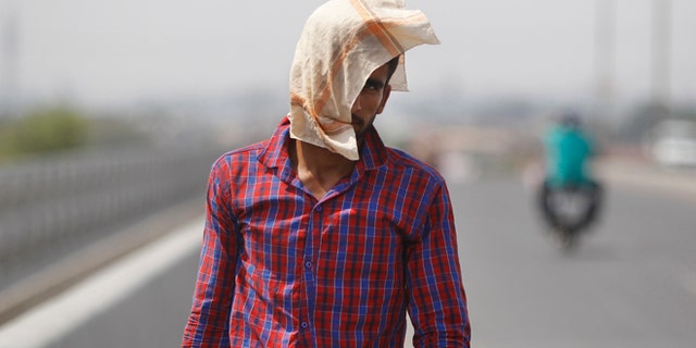 A man uses a cloth to protect himself from the sun during a hot summer day in Jammu, India, Friday, May 20, 2016. The prolonged heat wave this year has already killed hundreds and destroyed crops in more than 13 states, impacting hundreds of millions of Indians. (AP Photo/Channi Anand)