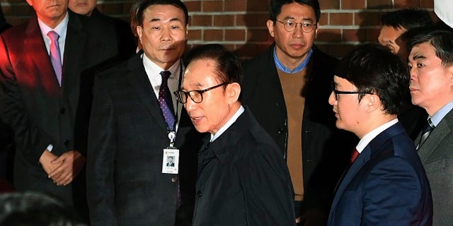 Former South Korean President Lee Myung-bak, centre, gets into a car as he is transferred to a detention centre, at his residence in Seoul early Friday March 23, 2018. A South Korea court issued an arrest warrant for ex-President Lee Myung-bak on corruption charges on Thursday. (Jung Yeon-je/Pool via AP)