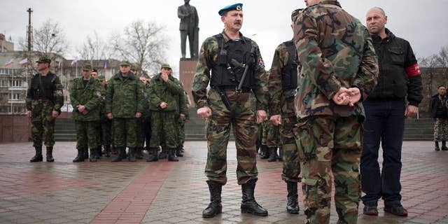Members of the Crimean self defense forces gather for their morning briefing prior to patrolling the city at Soviet Union founder Vladimir Lenin's statue in Simferopol, Crimea, early Thursday, March 27, 2014. Crimea’s government has decided to disband self-defense forces which provided help to the Russian military which have been occupying since late February. (AP Photo/Pavel Golovkin)
