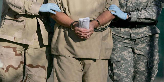 In this photo, reviewed by a U.S. Dept of Defense official, a shackled detainee is transported away from his annual Administrative Review Board hearing with U.S. officials, at Camp Delta detention center, Guantanamo Bay U.S. Naval Base, Cuba, Wednesday, Dec. 6, 2006. Each Guantanamo detainee has the option to participate in his own annual status review hearing which is part of the process for determining if a given detainee will continue to be held for another year. (AP Photo/Brennan Llinsley)
