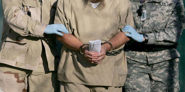 In this photo, reviewed by a U.S. Dept of Defense official, a shackled detainee is transported away from his annual Administrative Review Board hearing with U.S. officials, at Camp Delta detention center, Guantanamo Bay U.S. Naval Base, Cuba, Wednesday, Dec. 6, 2006. Each Guantanamo detainee has the option to participate in his own annual status review hearing which is part of the process for determining if a given detainee will continue to be held for another year. (AP Photo/Brennan Llinsley)