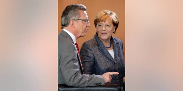 German Chancellor Angela Merkel, right, talks to German Interior Minister Thomas de Maiziere, left, at the beginning of a special meeting of the cabinet on migrants at the chancellery in Berlin, Germany, Tuesday, Sept. 15, 2015. (AP Photo/Michael Sohn)