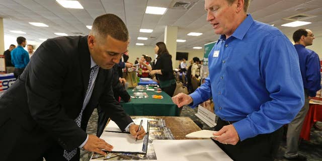 In this Friday, Feb. 6, 2015 photo, U.S. Marine Corps veteran Ignacio Yanes, left, writes information given by Jim Brooks, right, of the Small Business Administration at the annual Veterans Career and Resource Fair in Miami. The Labor Department issues its December report on job openings and labor turnover on Tuesday, Feb. 10, 2015. (AP Photo/Alan Diaz)