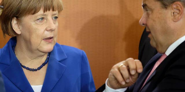 German Chancellor Angela Merkel, left, and Vice Chancellor and Economy Minister Sigmar Gabriel, right, talk as they arrive for the weekly cabinet meeting at the chancellery in Berlin, Germany, Wednesday, May 6, 2015. (AP Photo/Michael Sohn)