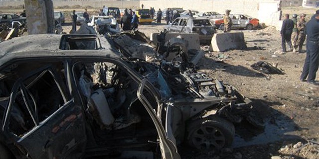 Mar. 20, 2012: People and security forces inspect the scene of a car bomb attack in Kirkuk.