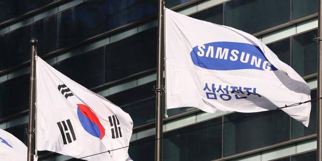 The company flag of Samsung Electronics flutters next to the South Korean national flag in Seoul, South Korea, Monday, Jan. 16, 2017. Prosecutors requested the arrest Monday of the de facto head of Samsung, South Korea's biggest company, on bribery and other charges in the influence-peddling scandal that led to the impeachment of the country's president. (AP Photo/Lee Jin-man)