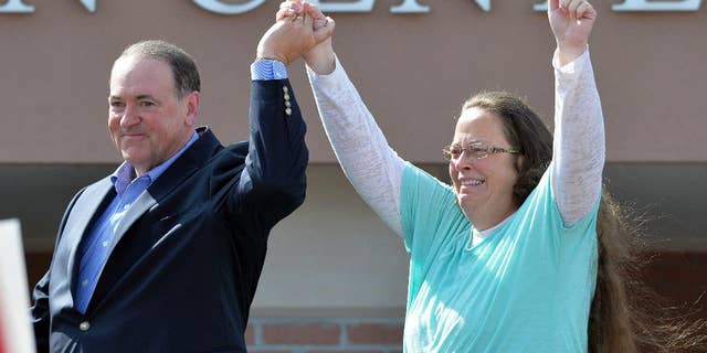 FILE - In this Tuesday, Sept. 8, 2015, file photo, Rowan County Clerk Kim Davis, with Republican presidential candidate Mike Huckabee at her side, greets the crowd after being released from the Carter County Detention Center, in Grayson, Ky. Having failed to ban same-sex marriage, many religious conservatives are now working to carve out protections for business owners and others who object to it on religious grounds. To some of them, Davis is a hero for her willingness to go to jail rather than issue marriage licenses. But others think Davis’ position as a government official makes her exactly the wrong figure to rally around. (AP Photo/Timothy D. Easley, File)