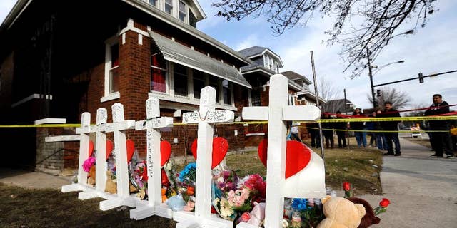 FILE - In this Feb. 7, 2016 file photo, mourners pay their respect outside a home in Chicago where six family members were found dead. On Thursday, May 19, 2016, Chicago police say they have arrested two suspects, a man and woman, in the Feb. 4 slayings. (AP Photo/Nam Y. Huh, File)